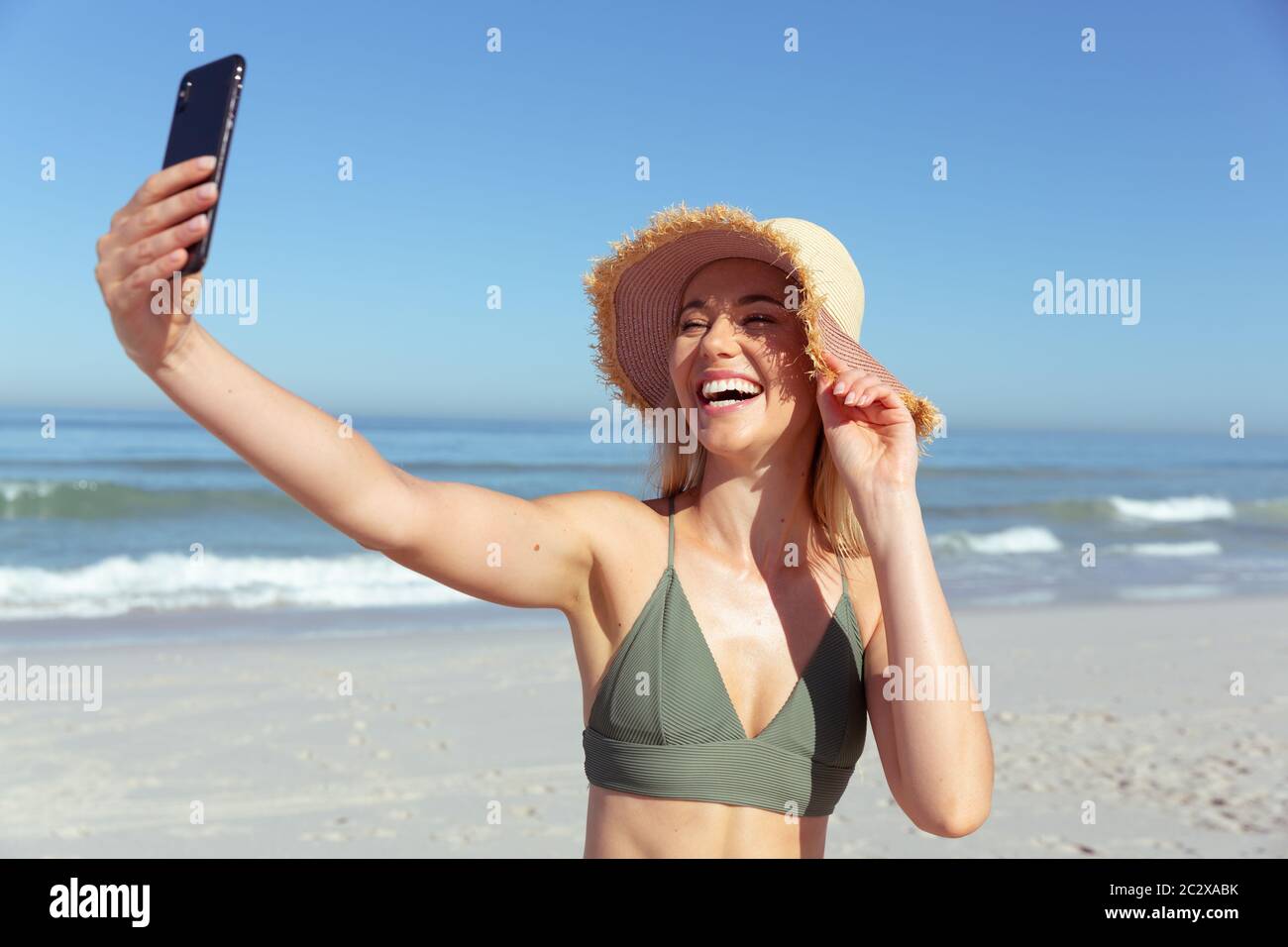 Caucasian woman using a phone and taking selfie at beach Stock Photo