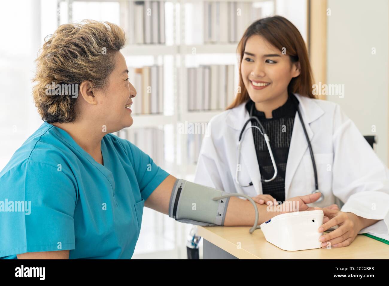 Female doctor measuring blood pressure of senior woman elderly at ...