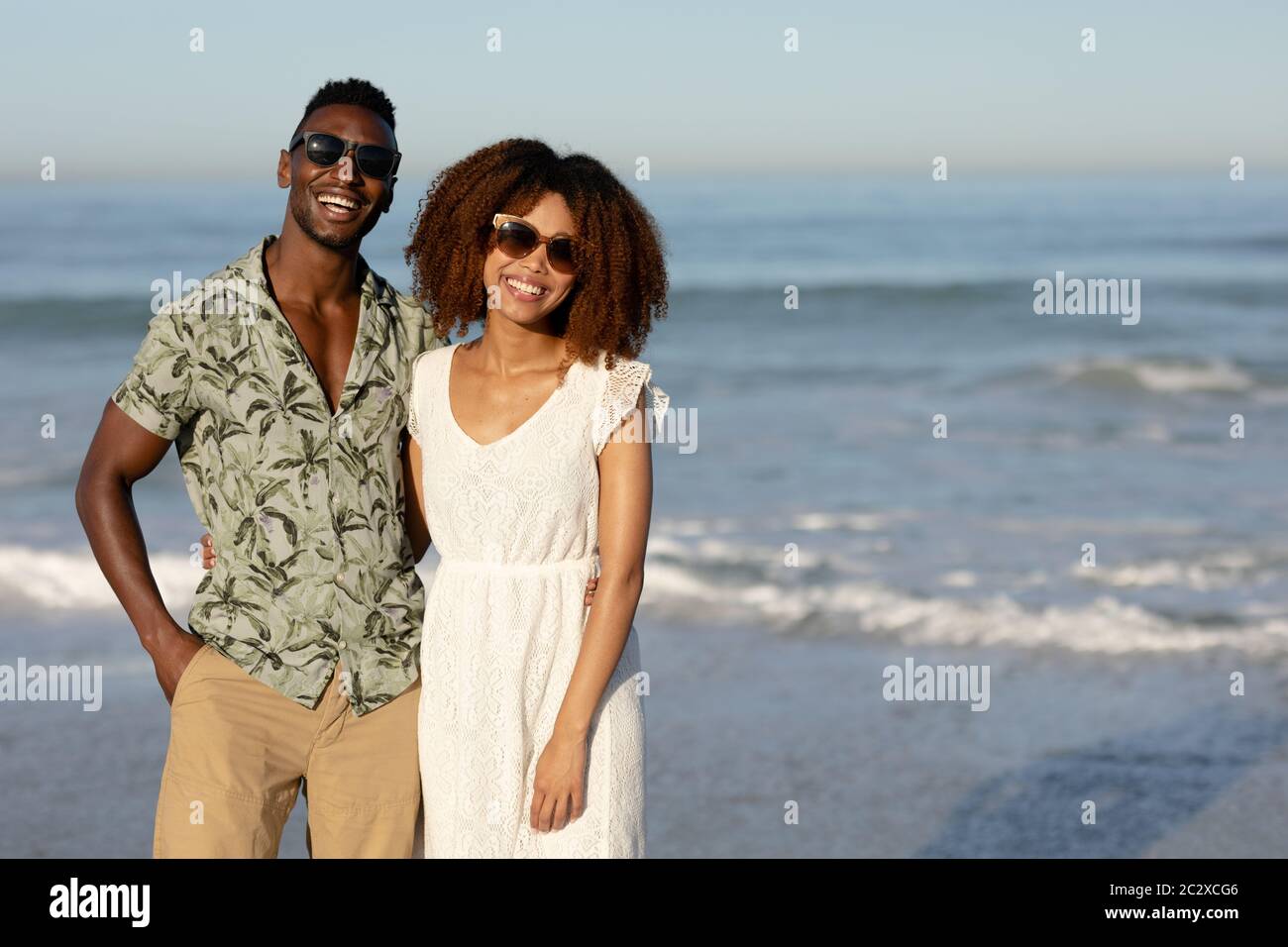 A mixed race couple posing and smiling on beach on a sunny day Stock Photo