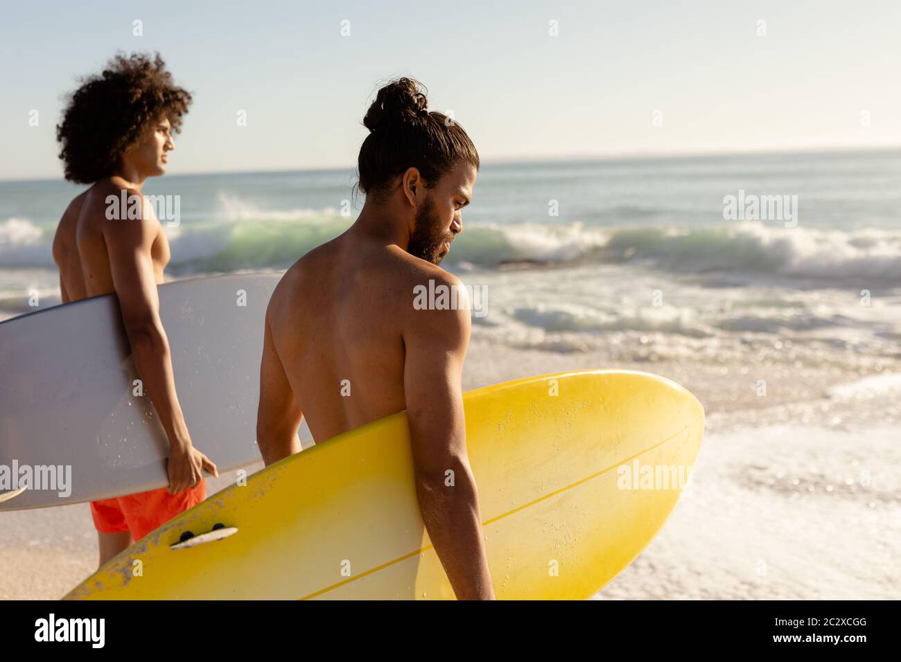 Multi-ethnic males holding surfboards on the beach Stock Photo
