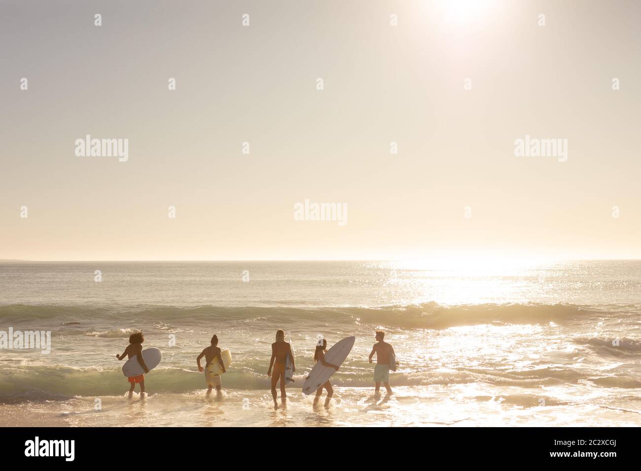 Multi-ethnic group of male and female, surfing on the beach Stock Photo