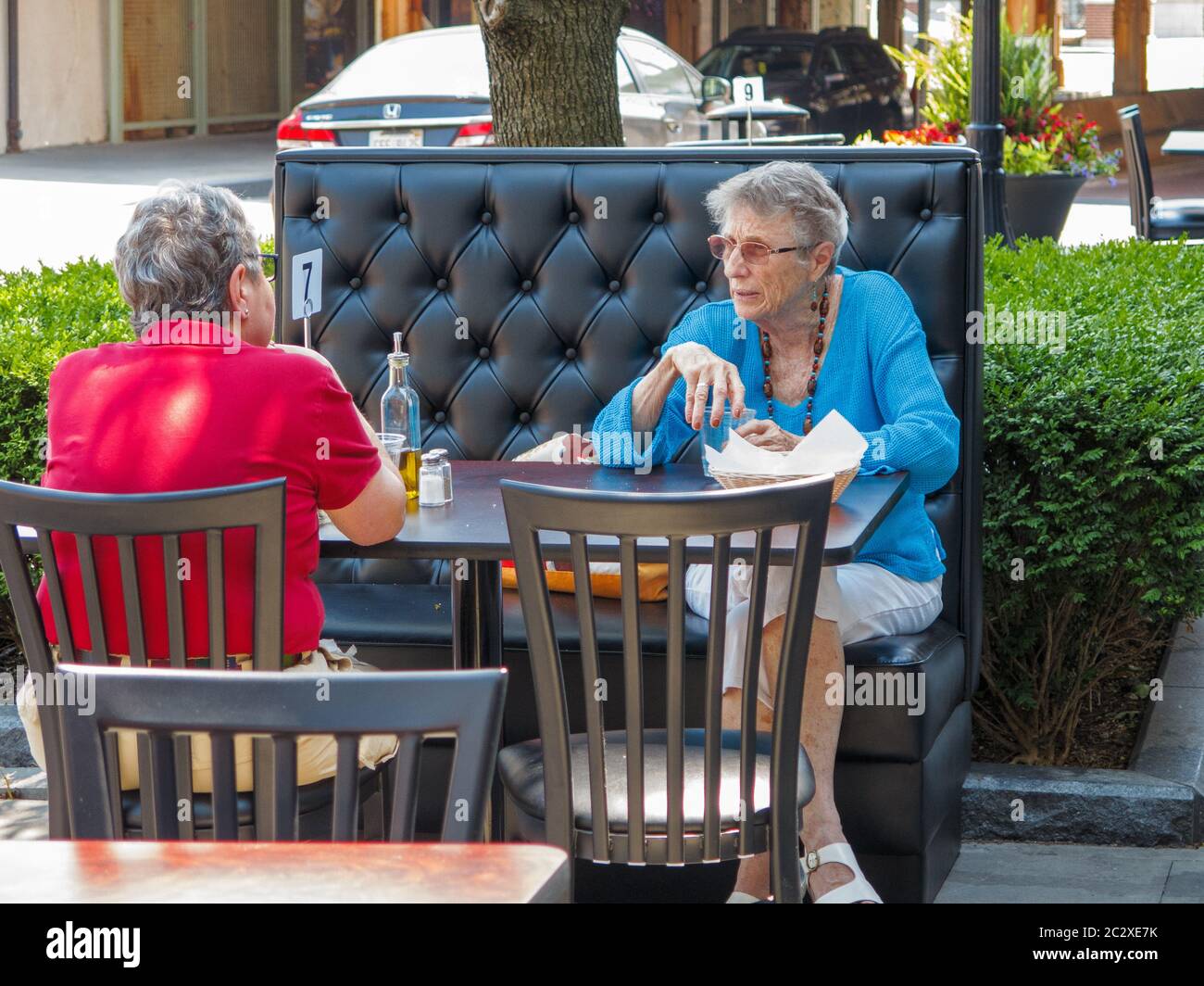 Oak Park, Illinois, USA. 17th June 2020.  Two women have lunch at a sidewalk café. Chicago area restaurants are now open for outside seating with proper social distancing. Servers must wear face masks. Illinois' COVID-19 infection rate is decreasing faster than other states due to vigorous stay at home and social distancing guidelines. Stock Photo