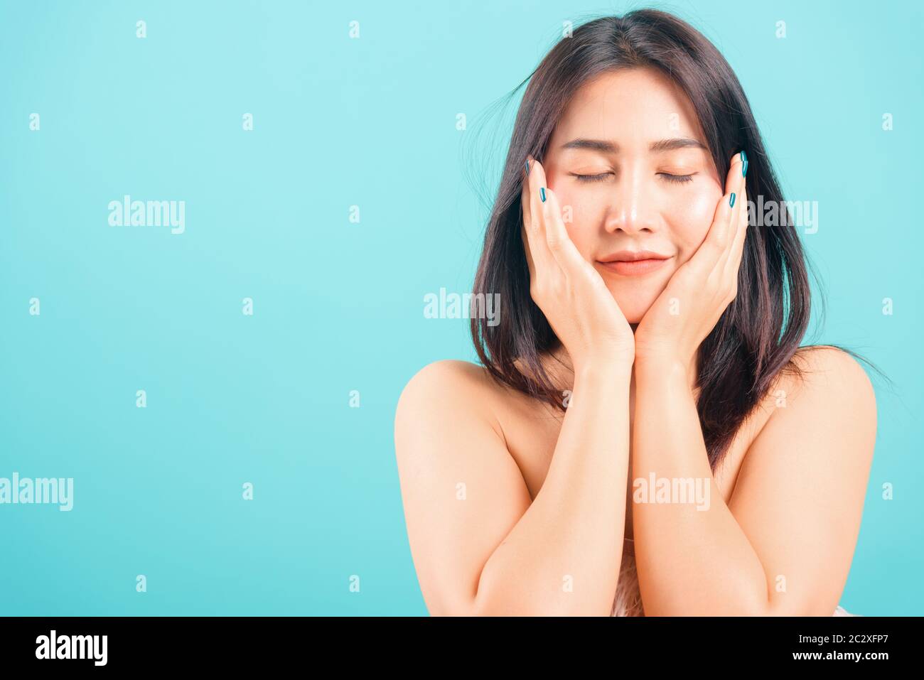 Smiling face Asian beautiful woman her touching face skin care on blue ...