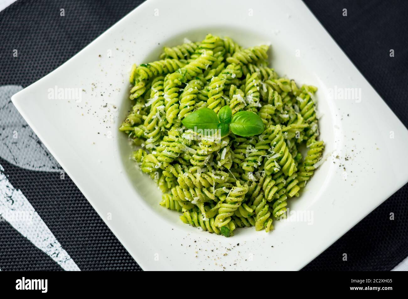 Rotini pesto pasta top view. Rotini pasta with basil pesto sauce, grated parmesan cheese and fresh pepper. This Italian dish makes a delicious meal. Stock Photo