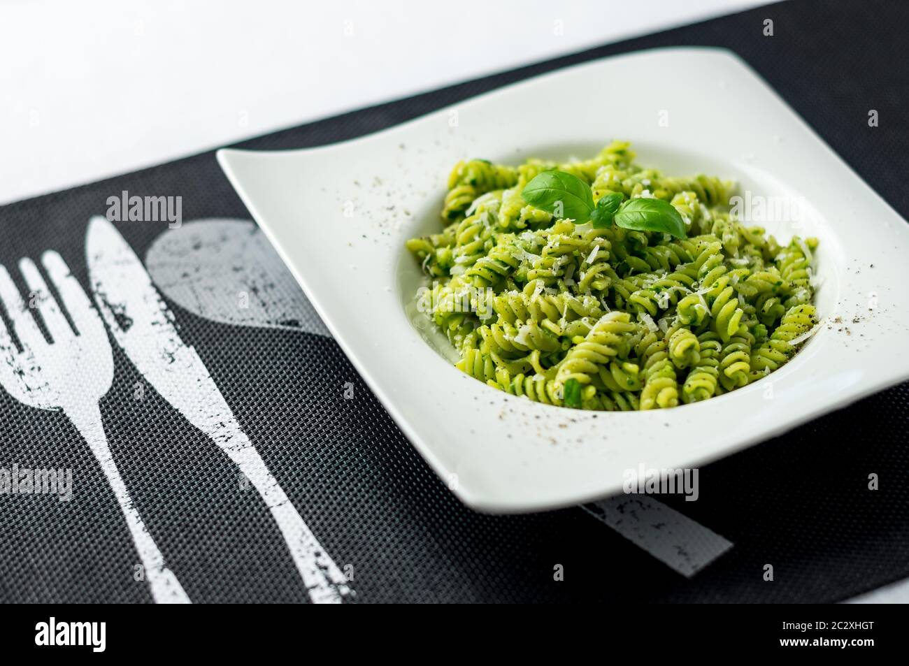 Fresh pesto pasta dish. Rotini pasta with basil pesto sauce, grated parmesan cheese and fresh pepper. This Italian dish makes a delicious meal. Stock Photo