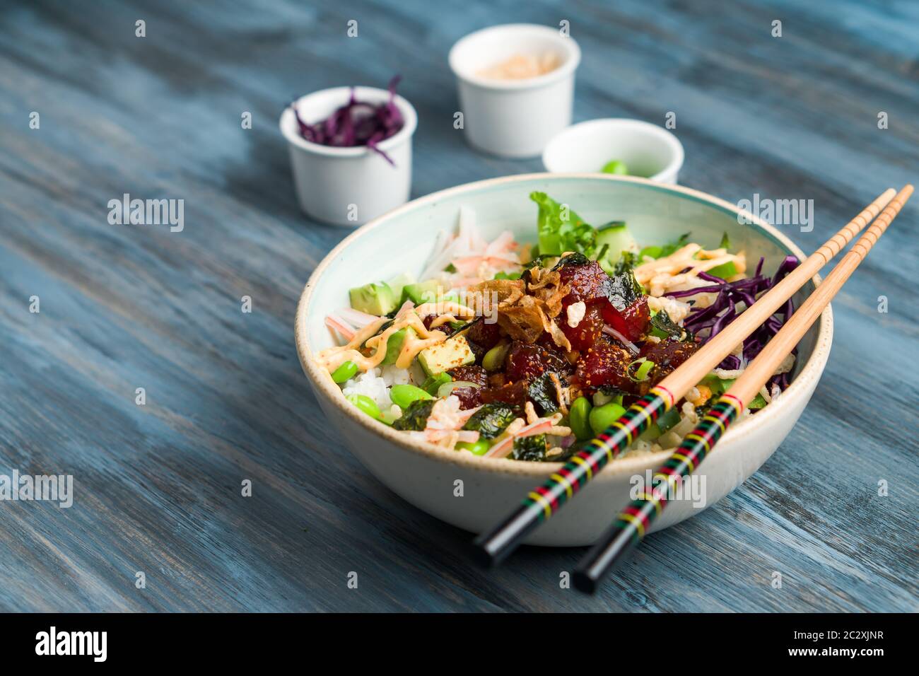 Poke bowl with chopsticks and ingredients. Poke is a traditional Hawaiian dish influenced by japanese and asian cuisine. Ahi poke is made of raw tuna Stock Photo