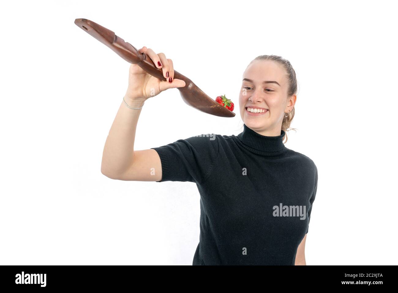 A young vegetarian woman is holding a huge spoon with a strawberry on it Stock Photo