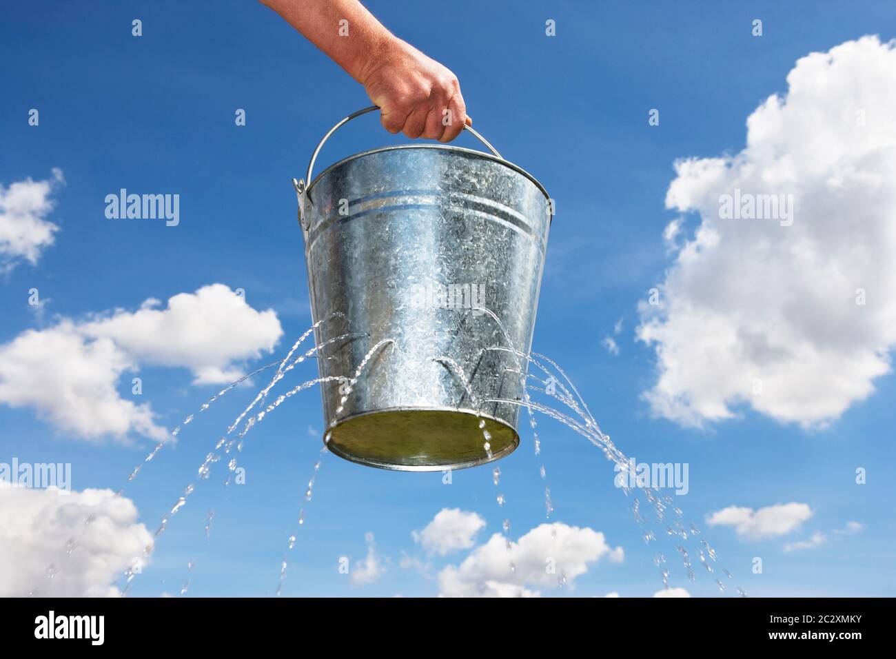 Man holding bucket with holes leaking water Stock Photo