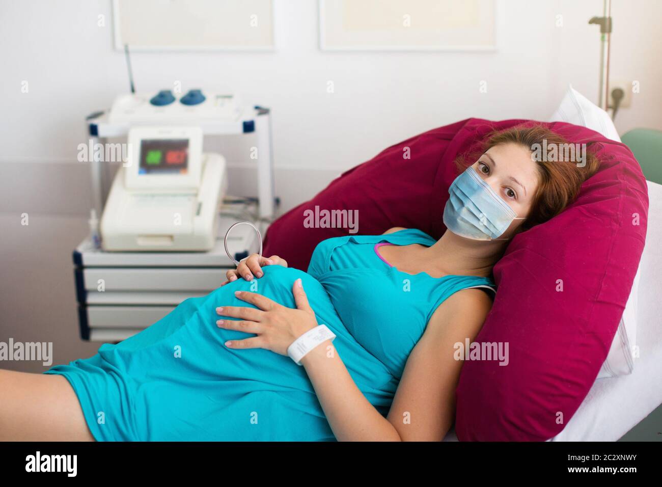 Pregnant patient in face mask in a hospital at doctor visit during coronavirus outbreak. Mother