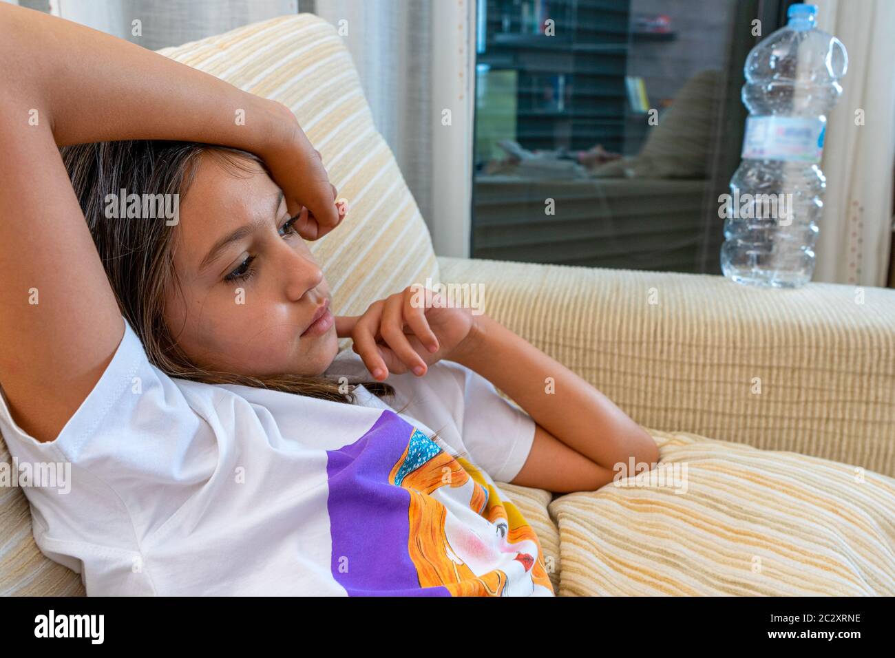 Portrait of beautiful little girl posing on white sofa in home living ...