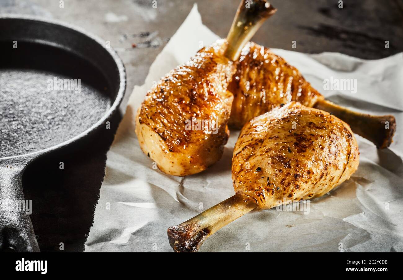 Three spicy seasoned grilled chicken legs on crumpled white paper