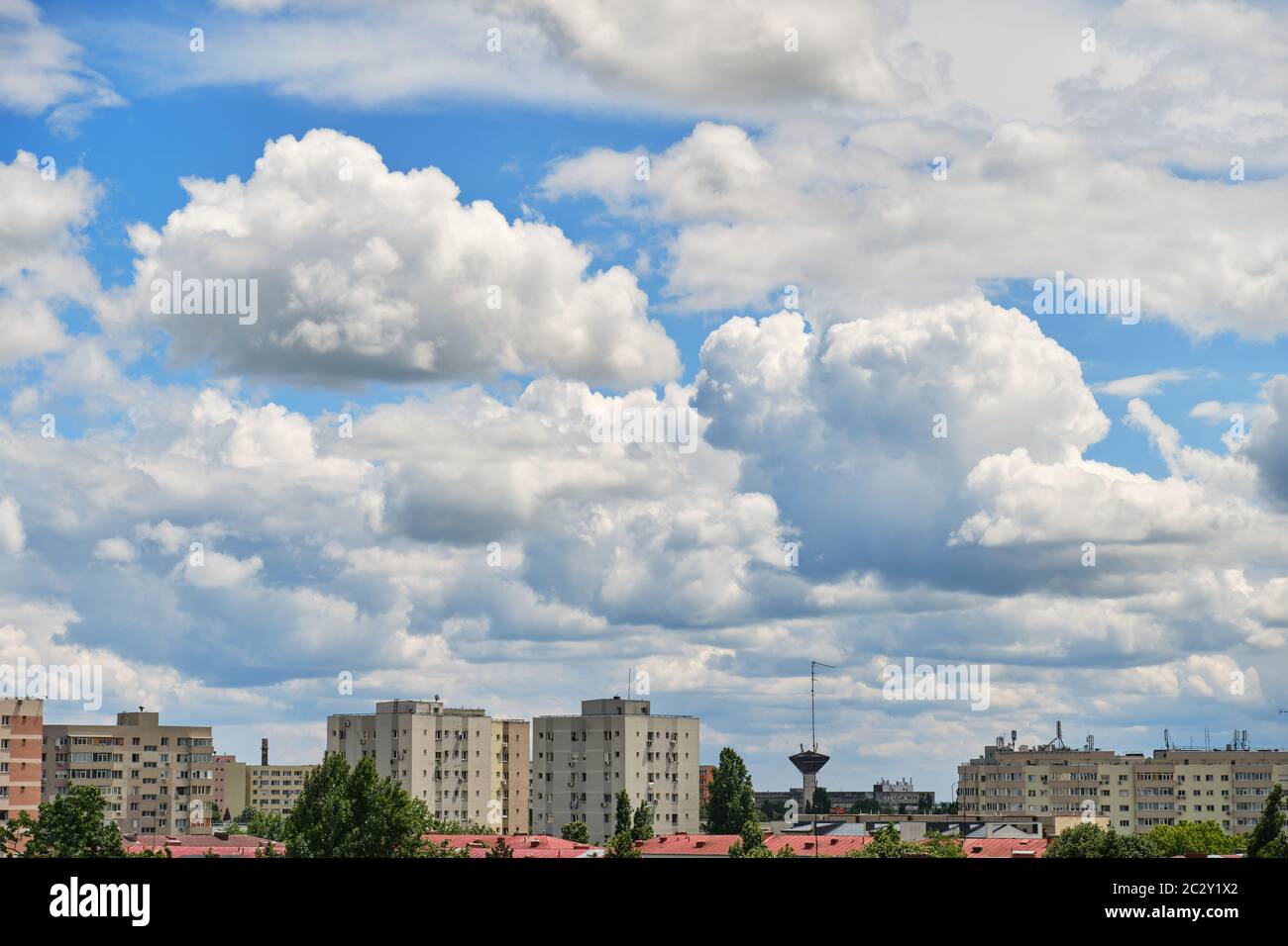 Stratocumulus clouds form a layer and move fast from left to right over city buildings, in a residential neighborhood of Bucharest, Romania, Eastern E Stock Photo