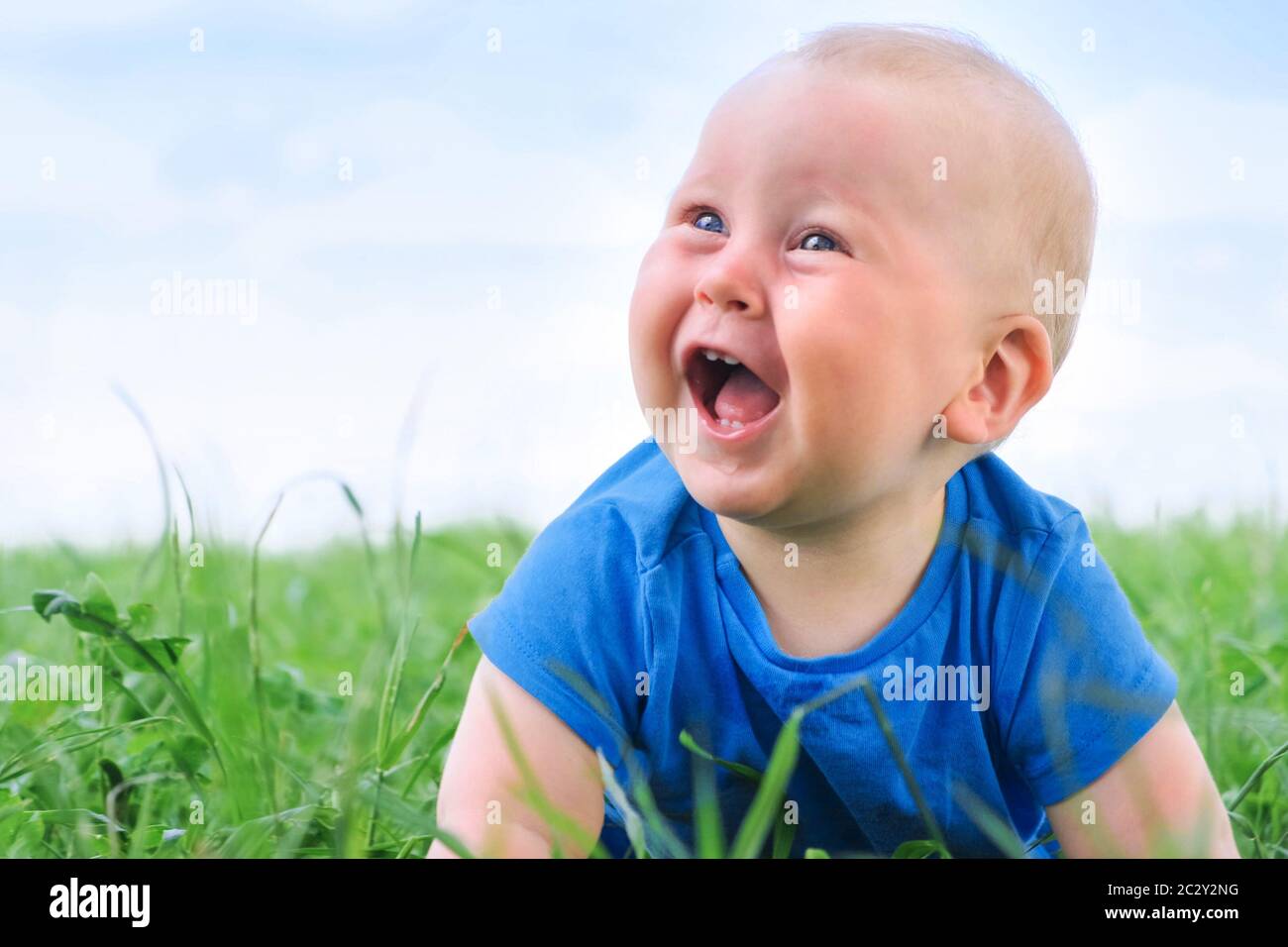 Excited baby sitting crawling on green grass and smiling broadly. cute ...