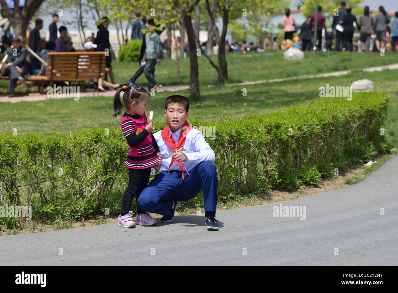 Pyongyang, North Korea - May 1, 2019: Young boy, member of the Young Pioneer Corps and his little sister with ice cream on a city street Stock Photo