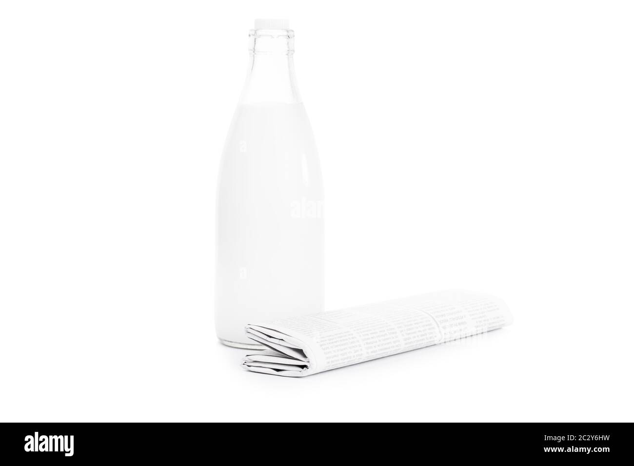 Close up shot of a rolled up newspaper and an old school bottle of milk, isolated on white background. Stock Photo