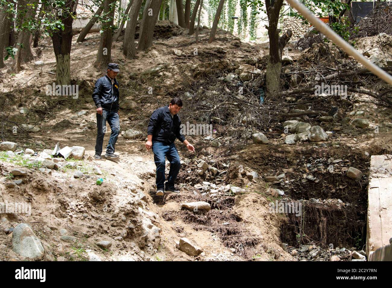 (200618) -- TAXKORGAN, June 18, 2020 (Xinhua) -- Amirjan Elim (front) and a villager are on their way to clean the watercourse in Datung Township of Taxkorgan Tajik Autonomous County, northwest China's Xinjiang Uygur Autonomous Region, June 13, 2020. Located deep in a valley, Datung Township is surrounded by towering mountains. These mountains have become a barrier for local residents to access to the national power grid. To solve the power supply problem, the town in late 1980s organized villagers to build a ditch along the Datung River and introduced a hydropower generator. For years, the sm Stock Photo