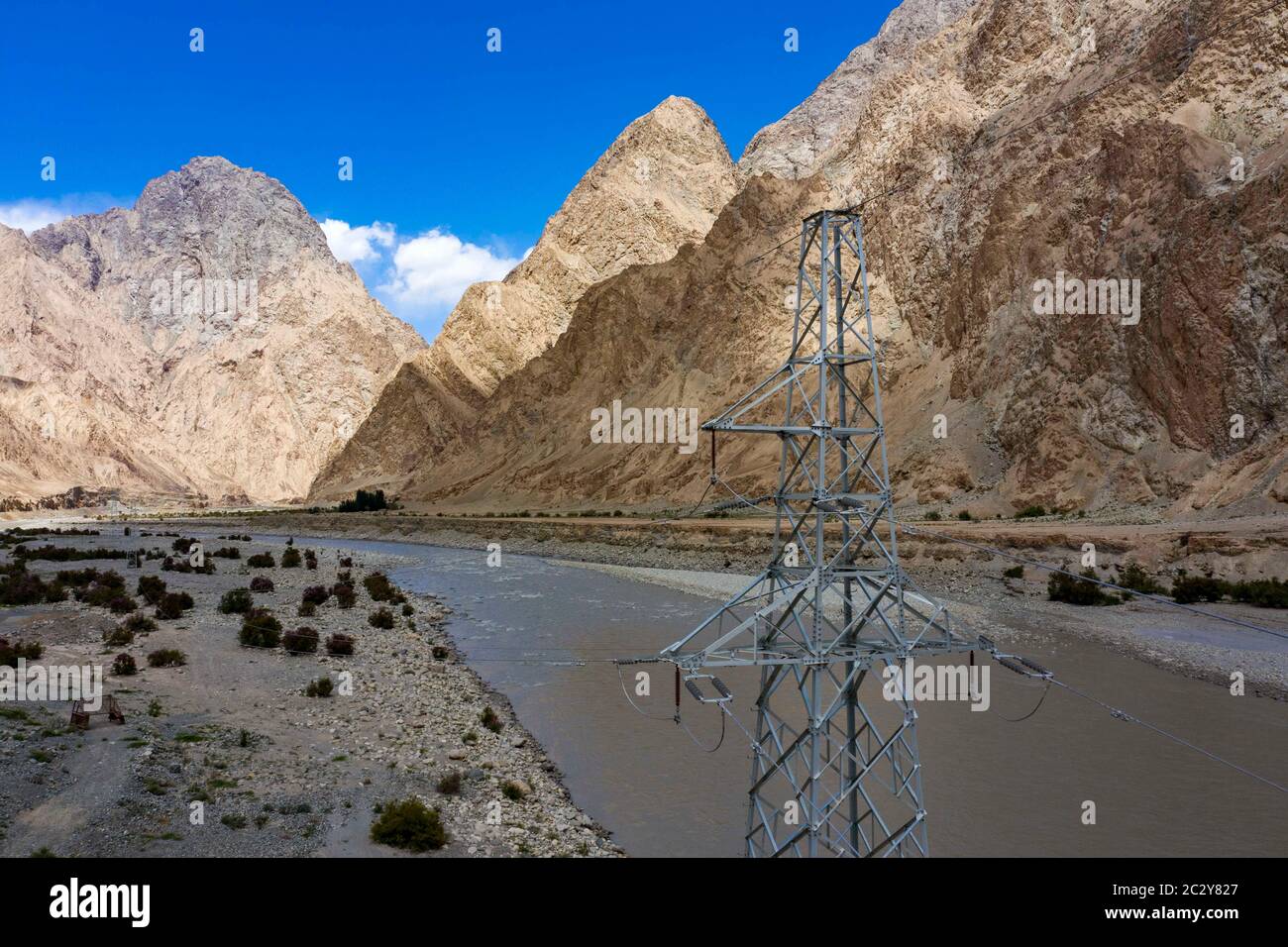 (200618) -- TAXKORGAN, June 18, 2020 (Xinhua) -- Aerial photo taken on June 14, 2020 shows an electric transmission tower in Datung Township of Taxkorgan Tajik Autonomous County, northwest China's Xinjiang Uygur Autonomous Region. Located deep in a valley, Datung Township is surrounded by towering mountains. These mountains have become a barrier for local residents to access to the national power grid. To solve the power supply problem, the town in late 1980s organized villagers to build a ditch along the Datung River and introduced a hydropower generator. For years, the small-sized hydropower Stock Photo