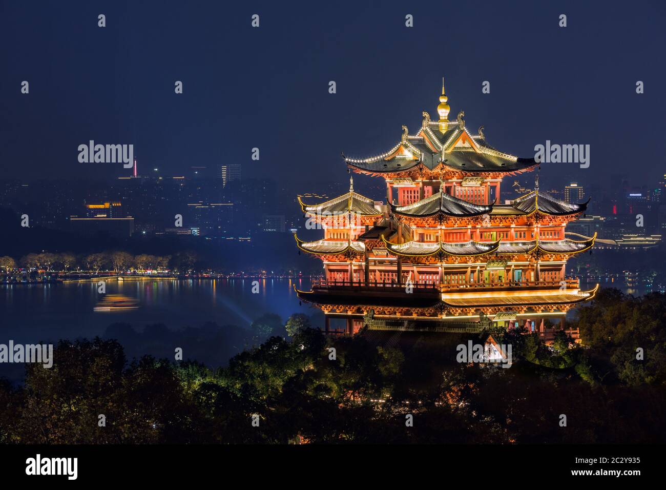 Night view of illuminated Cheng Huang Ge (City God Pavillion) with West Lake and city skyline on background, Hangzhou, China Stock Photo