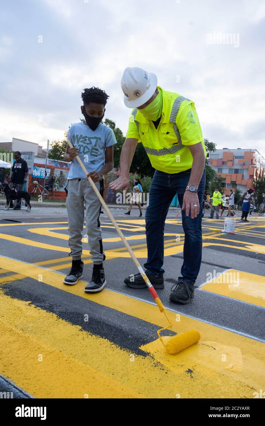 City of Austin Transportation Director Robert Spillar teaches Tobias Jackson-Woods how to use a paint roller as artists paint a mural on east 11th Street near downtown Austin that says "Black Artists Matter," two days after the group painted "Black Austin Matters" in large yellow letters on Congress Avenue in the heart of downtown. Stock Photo