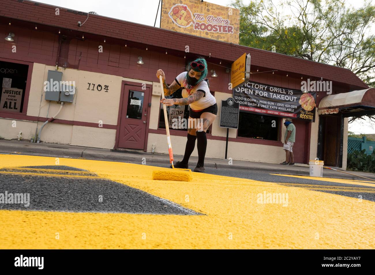 Austin, TX USA June 18, 2020: Street artist Vanessa Mora helps paint a mural in front of the legendary Victory Grill on east 11th St that says 'Black Artists Matters' on two days after the group painted 'Black Austin Matters' in large yellow letters on Congress Avenue, the Austin, TX main street. Several other U.S. cities have created murals starting when 'Black Lives Matter' was painted near the White House in Washington, DC Credit: Bob Daemmrich/Alamy Live News Stock Photo