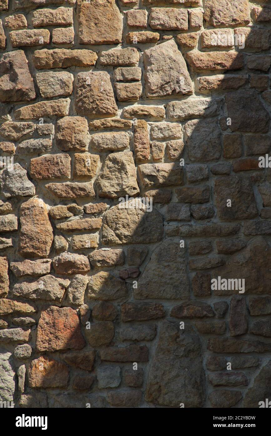 Dry stone wall texture background, in searing light and diagonal shadow. Stock Photo