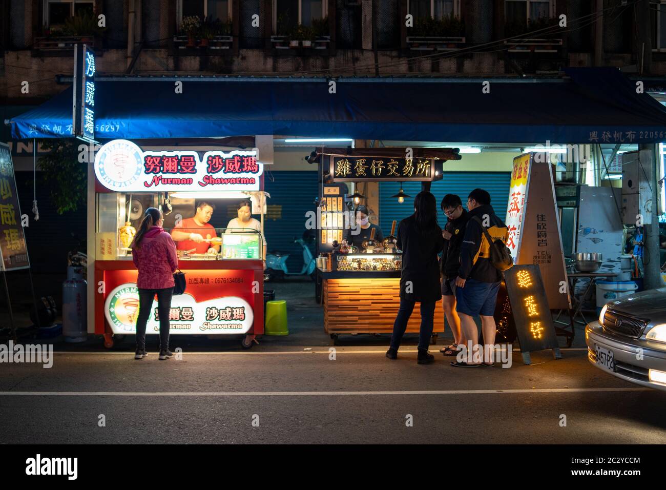 Street food vendors selling food at the side of a street with customers