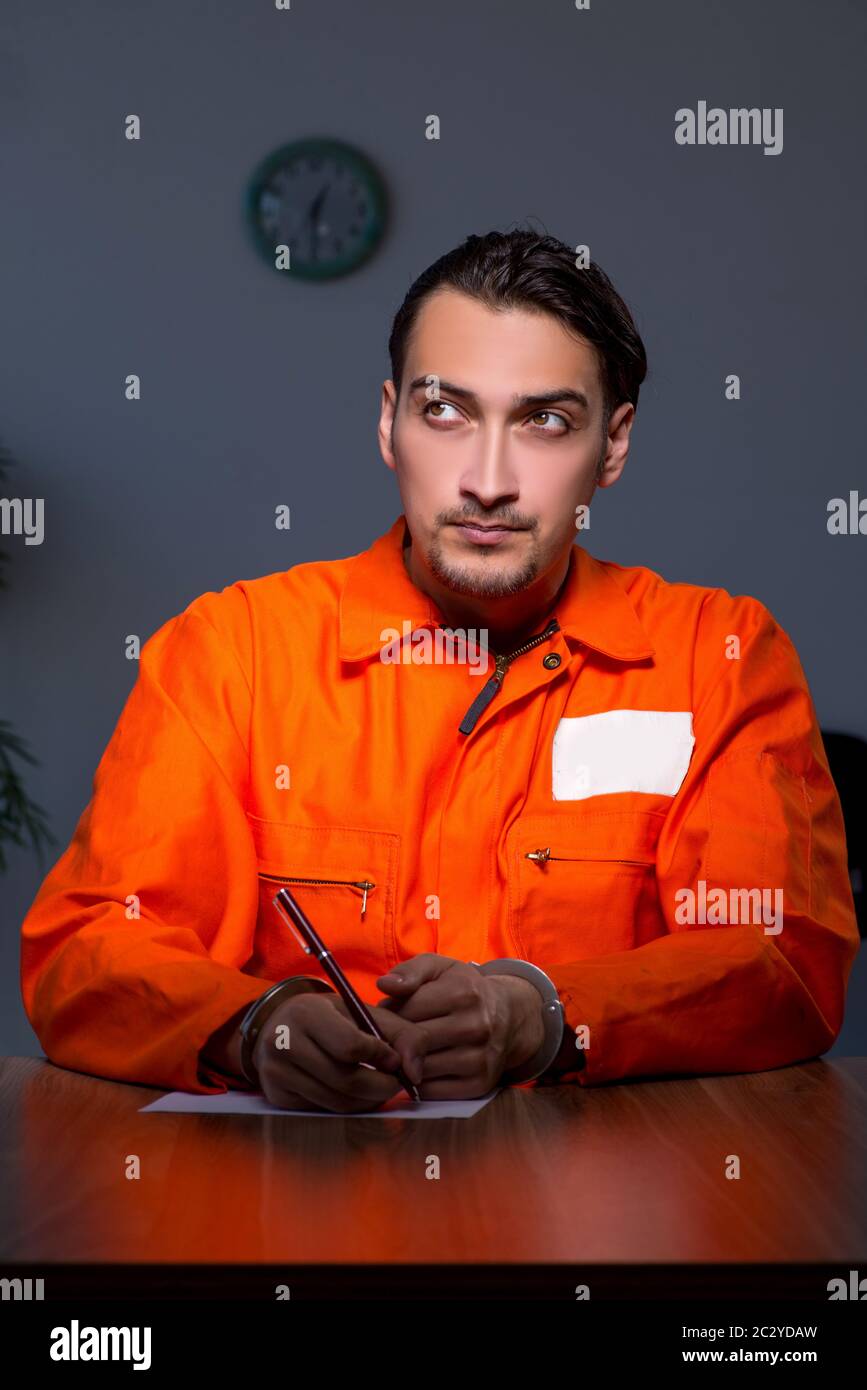 Young convict man sitting in dark room Stock Photo