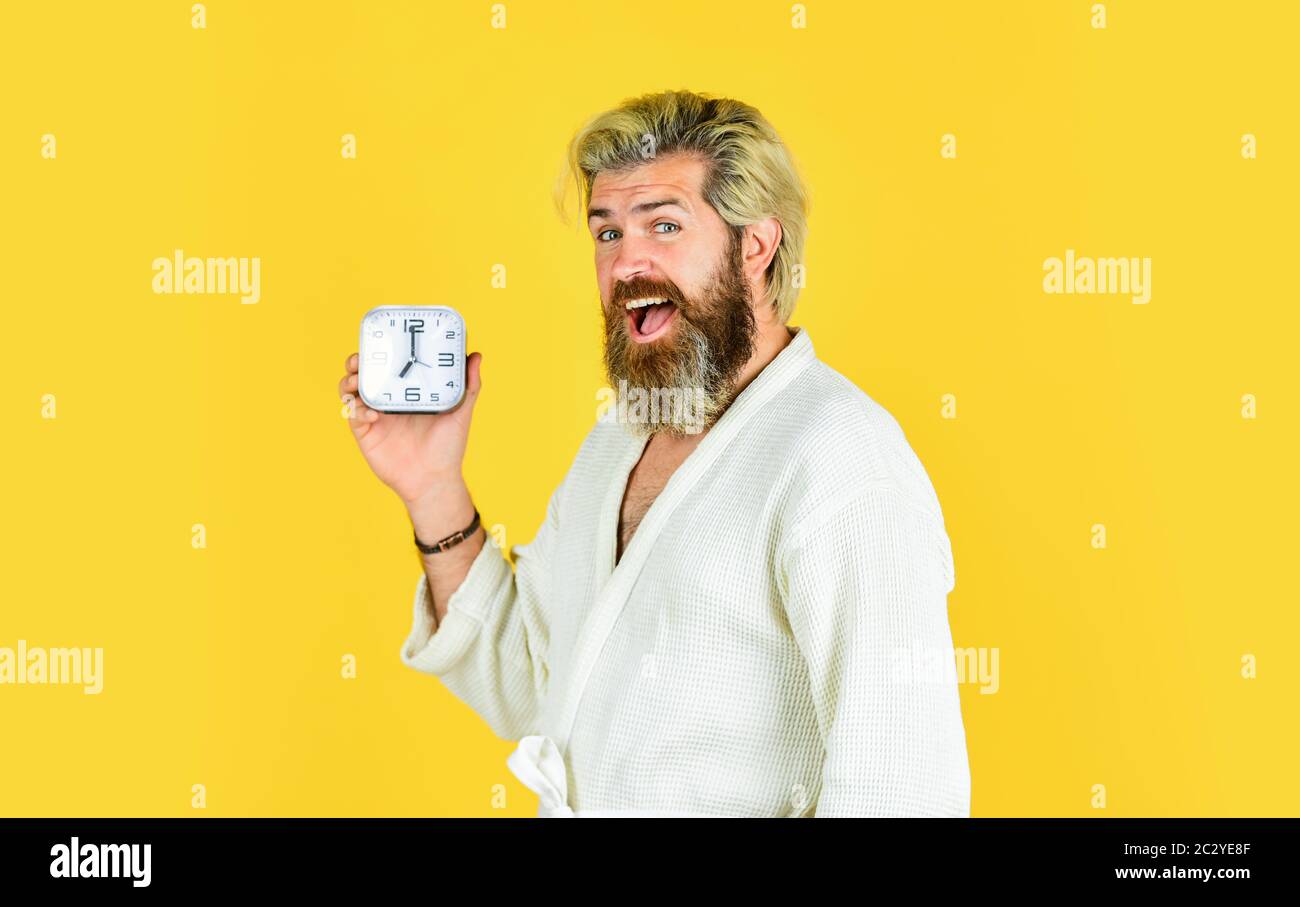 handsome happy man indoors wake up turn off the alarm clock. Tired man in bedroom not happy. suffer insomnia and sleep disorder. bedtime. Destroy the Clock. Does changing clock mess with your health. Stock Photo