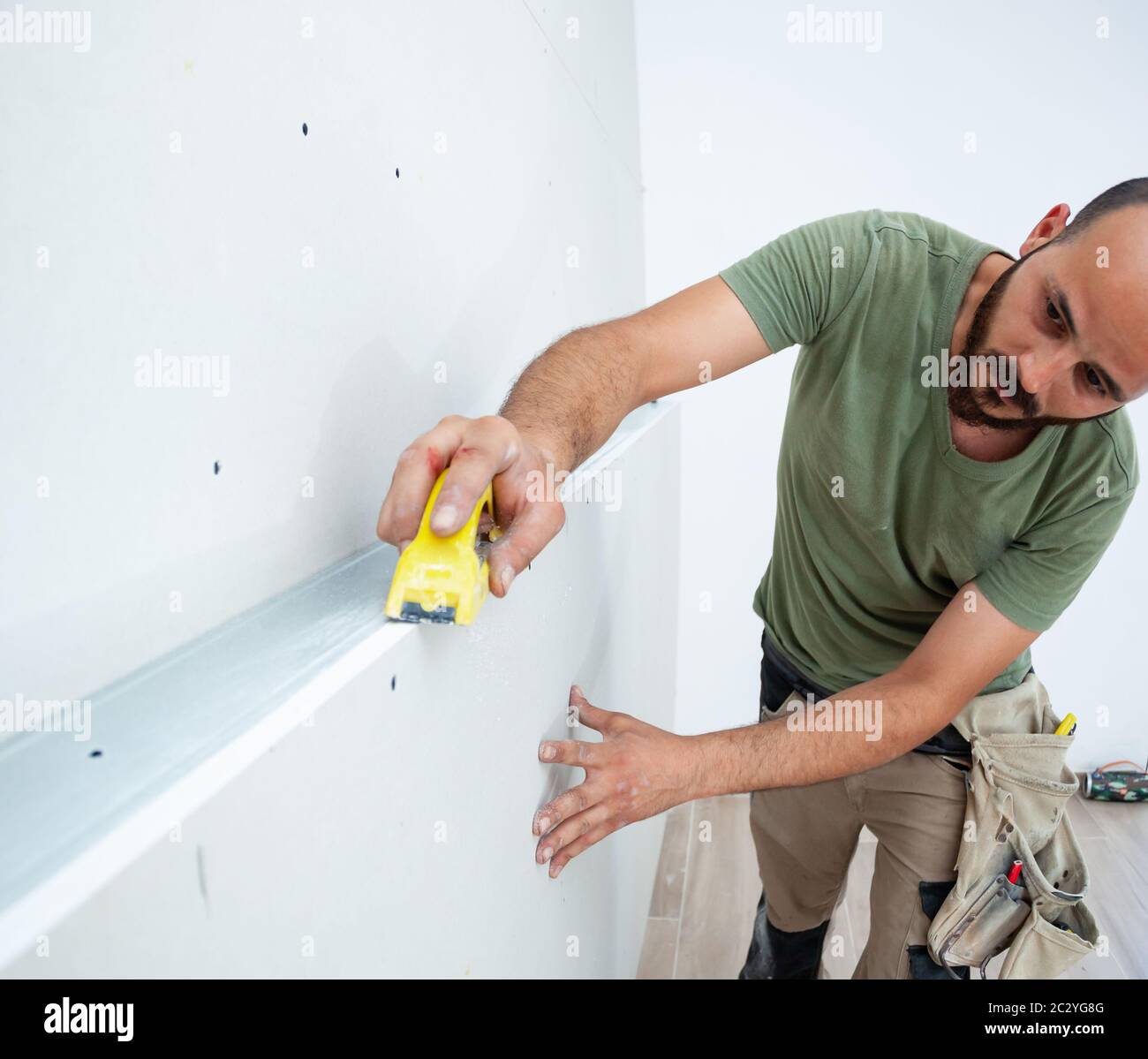 Worker building plasterboard wall. Working with cutting tools, fixing and measuring for drywall. Stock Photo