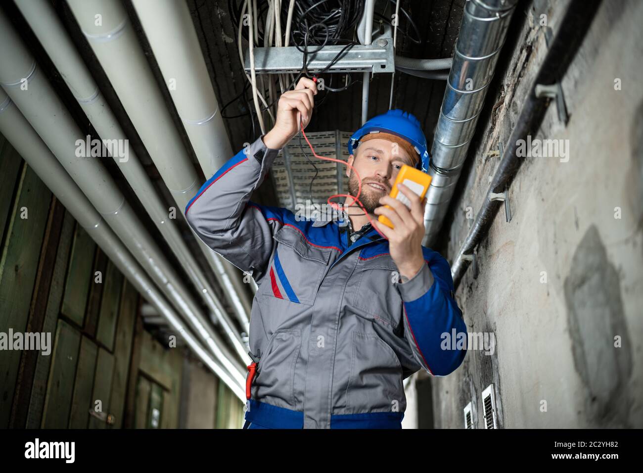 Male Worker Wearing Hard Hat Using Multimeter Stock Photo