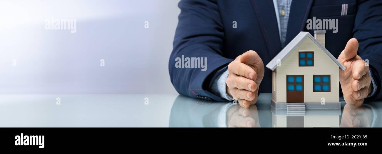 Young Businessman Protecting Model Of The House Stock Photo
