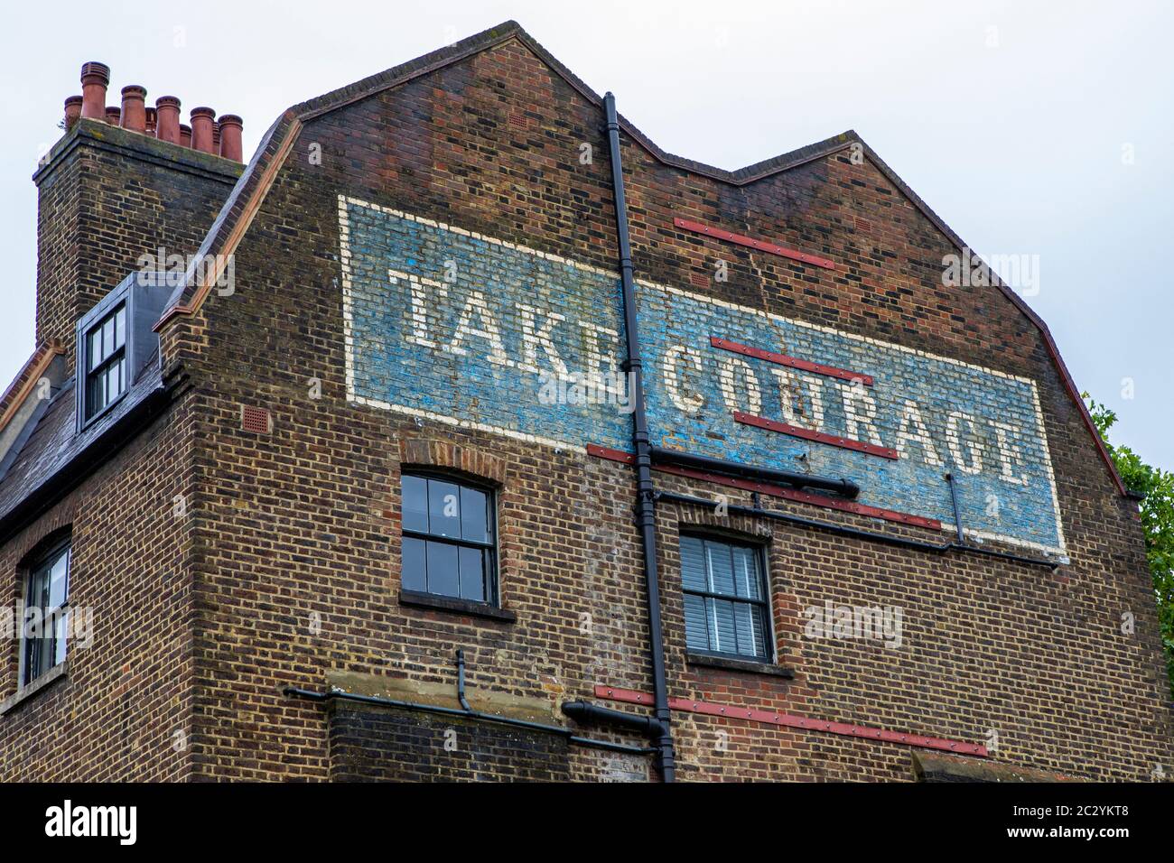 Looking up at the vintage Take Courage ghost sign, located on Redcross Street in London, UK. Stock Photo