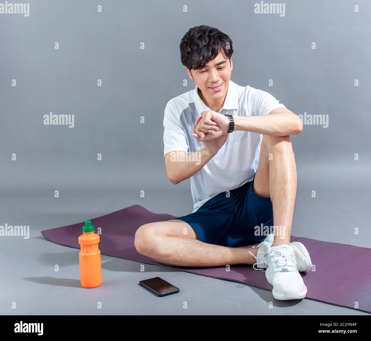 young man runner doing stretching exercise and checking smart watch Stock Photo