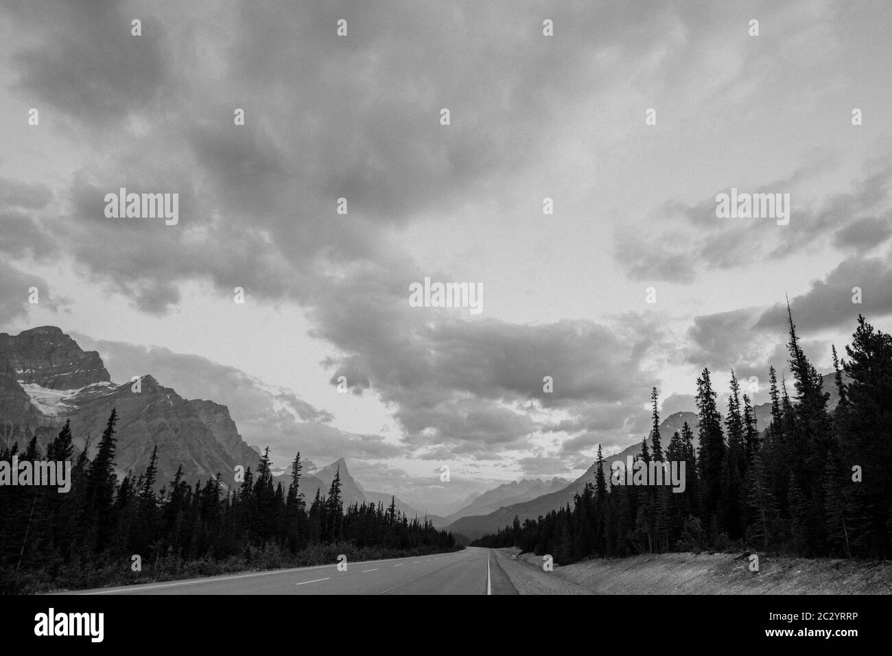 Road passing through Banff National Park landscape against cloudy sky, Banff, Alberta, Canada Stock Photo