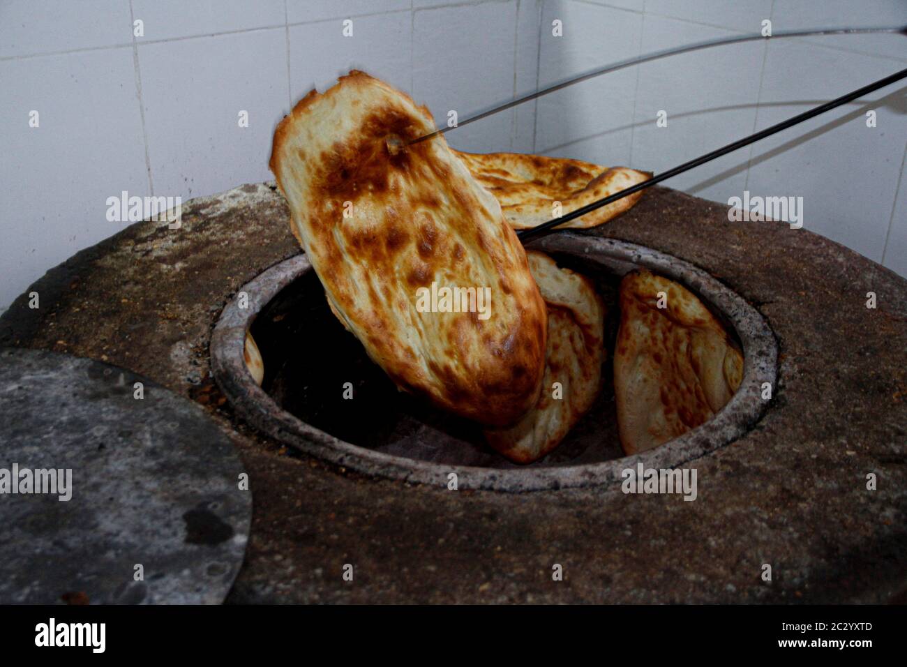 Taking caucasian tandir bread out with equipments Stock Photo