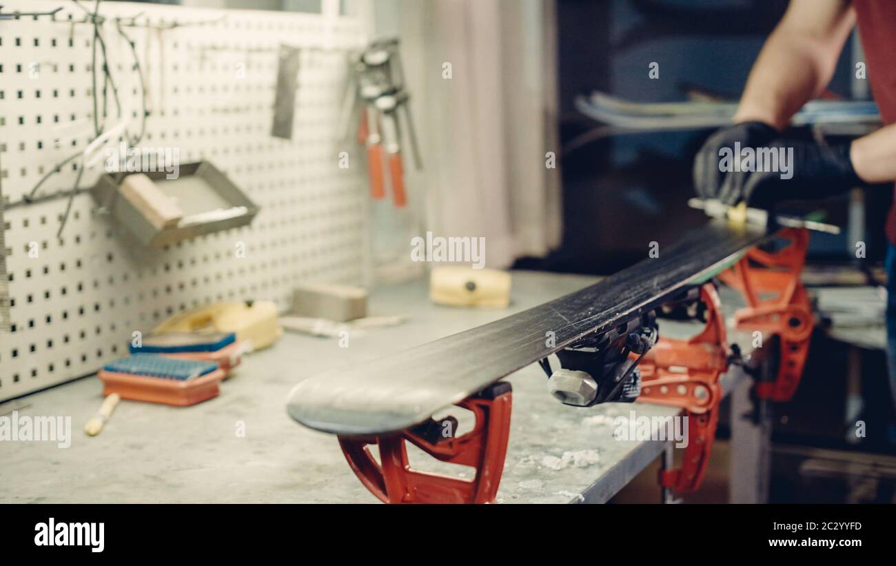 Male worker of ski service doing sharpening and repair of skis