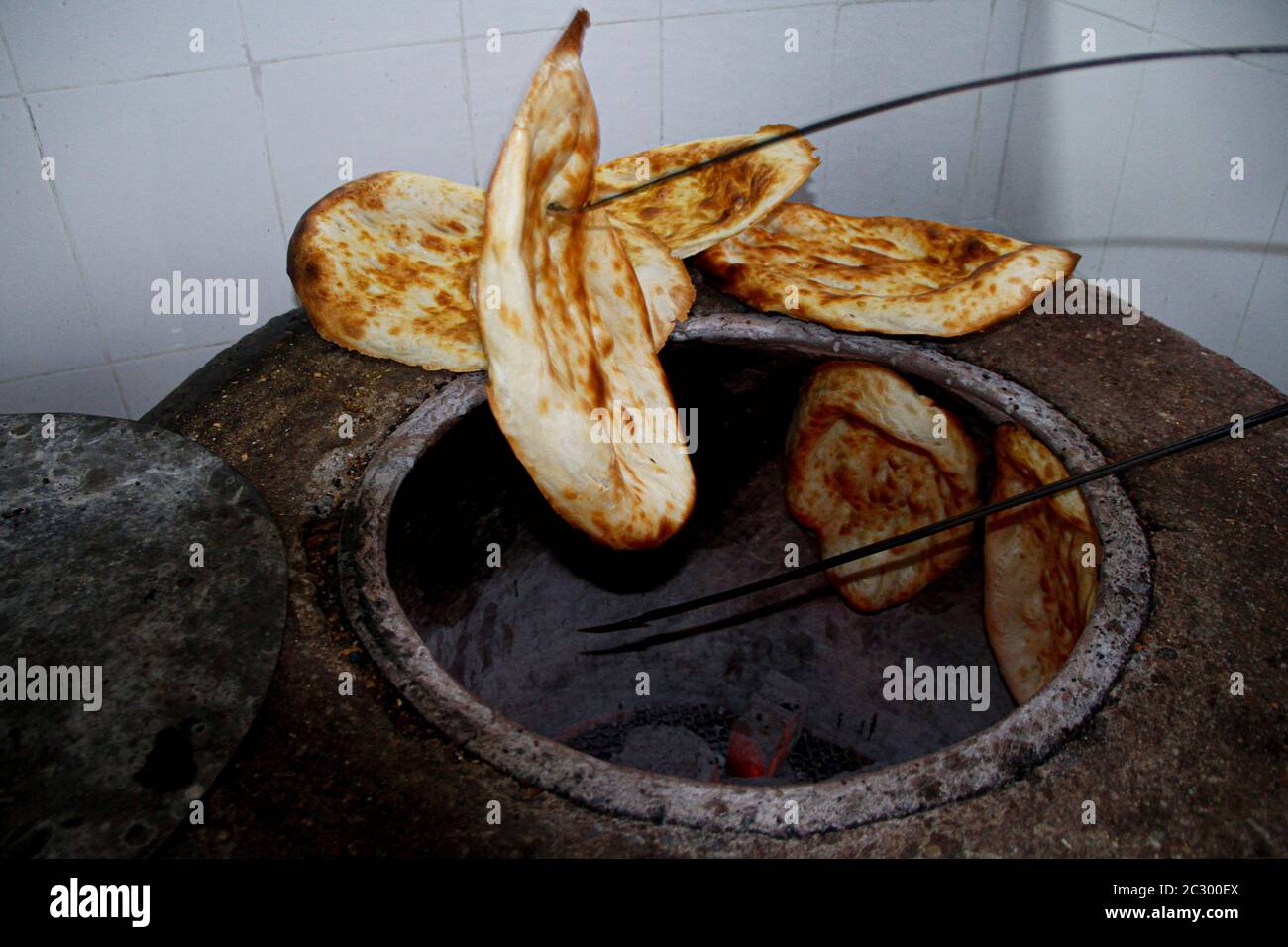 Finely cooked caucasian tandir bread taking out of the pan Stock Photo