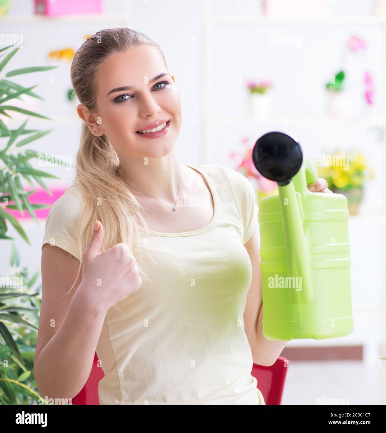 Young woman watering plants in her garden Stock Photo - Alamy