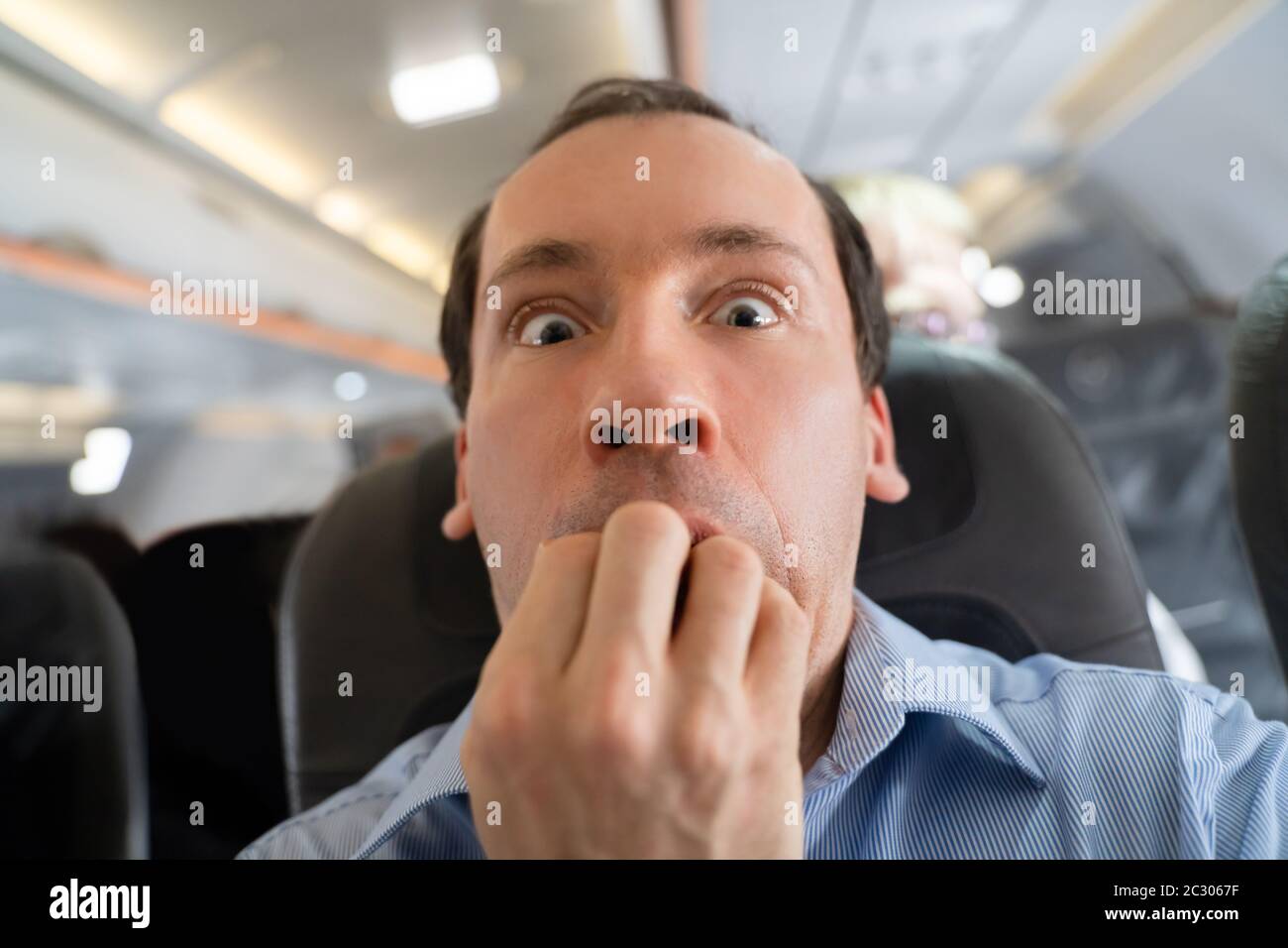 Young Man Having Anxiety Attack In Airplane Stock Photo