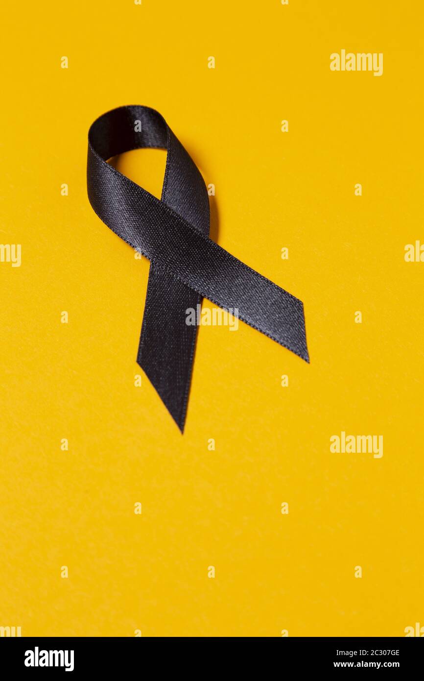 A black awareness ribbon isolated on orange background Stock Photo