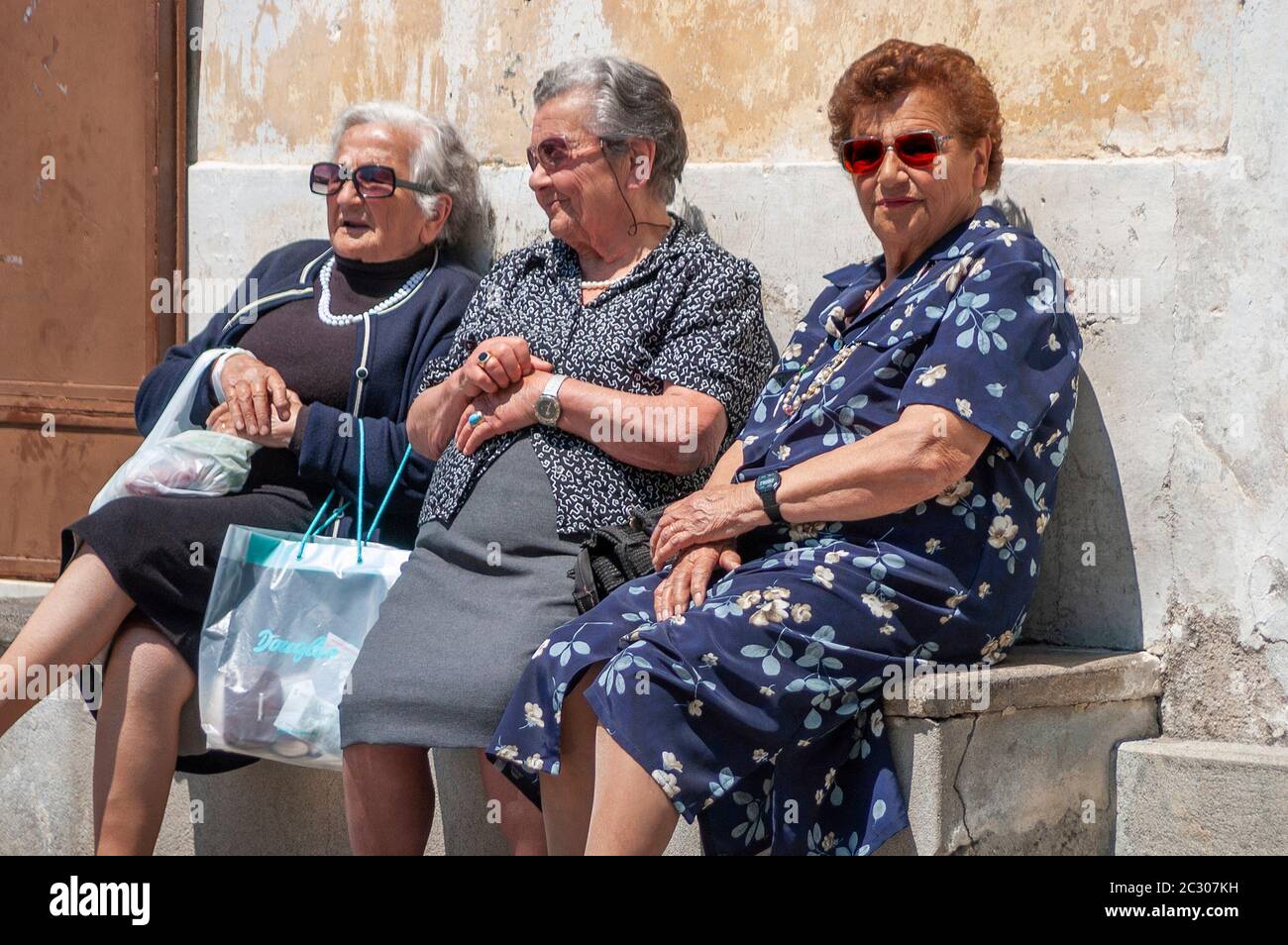 Three elderly Italian ladies rest of a stone seat in the famous holiday town of Ravello in Southern Italy Stock Photo