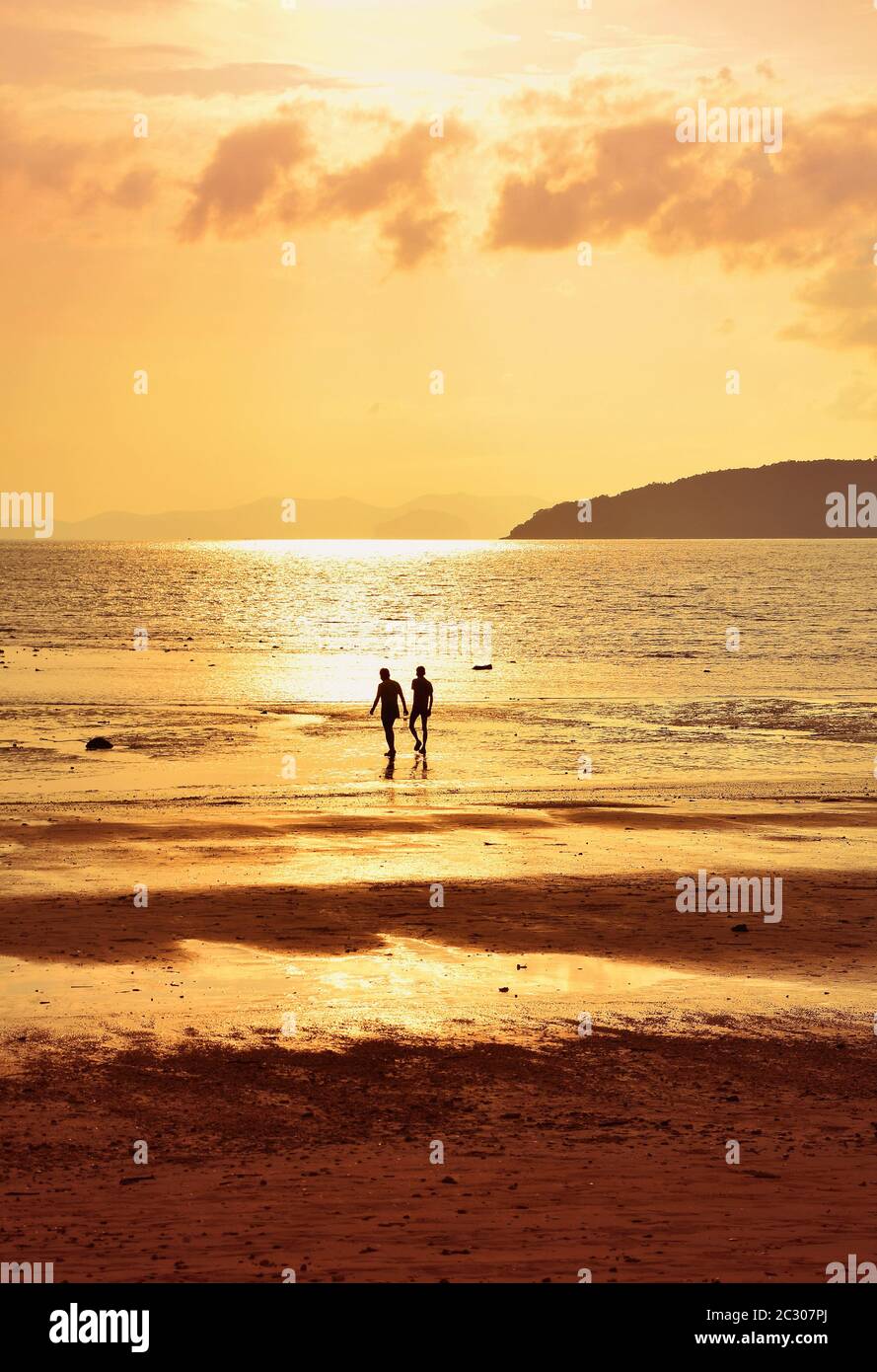Silhouette of two people walking on sunset sea shore, rear view Stock ...