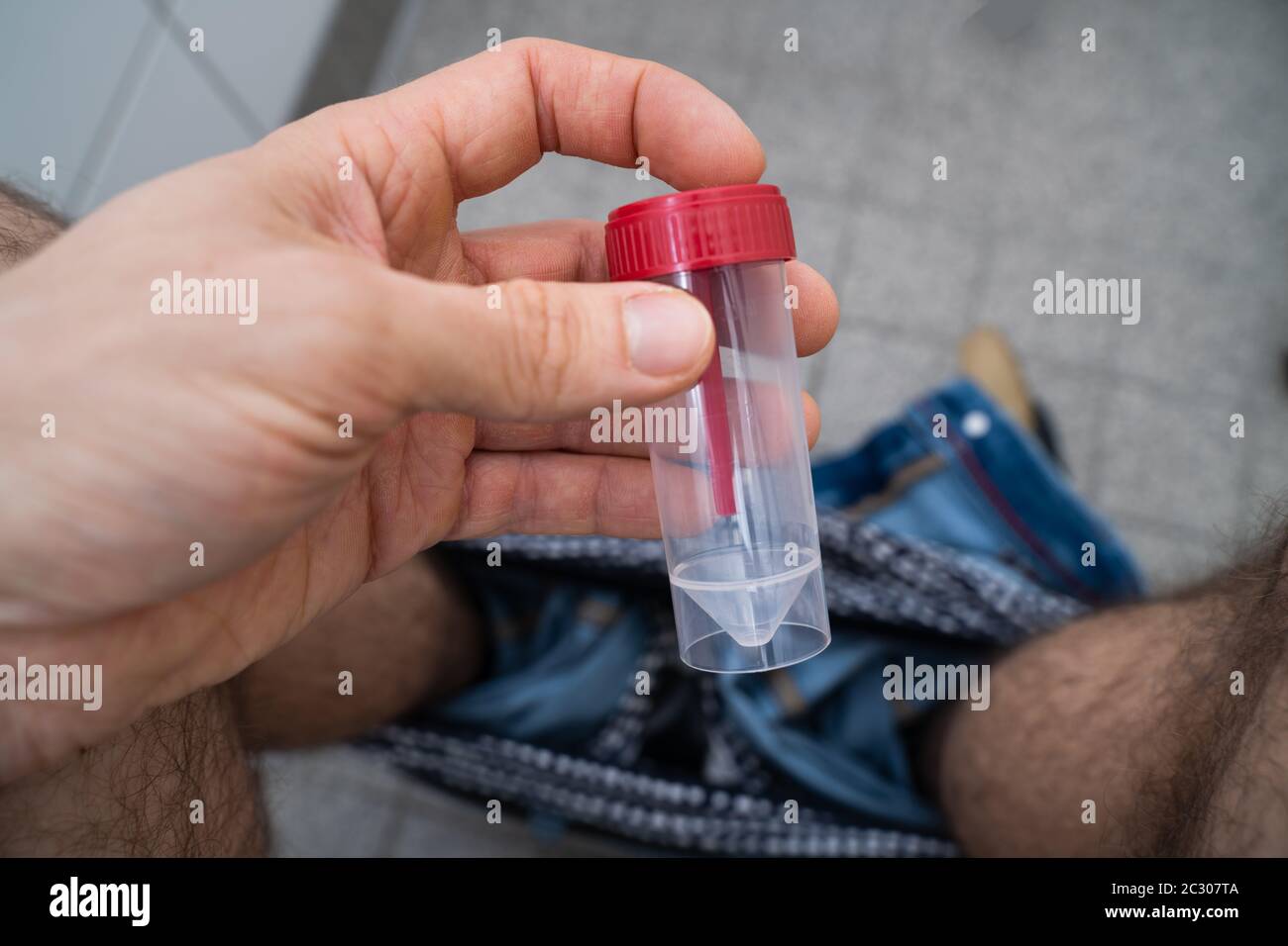 Stool Sample Container In Hands Of Man Sitting On Toilet Stock Photo