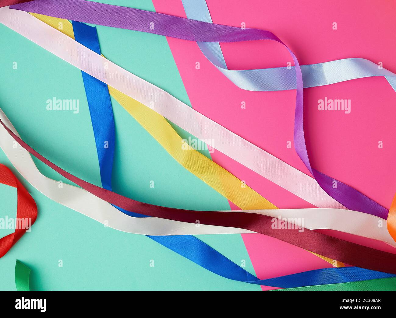 many silk multi-colored ribbons on a colored background, top view Stock Photo