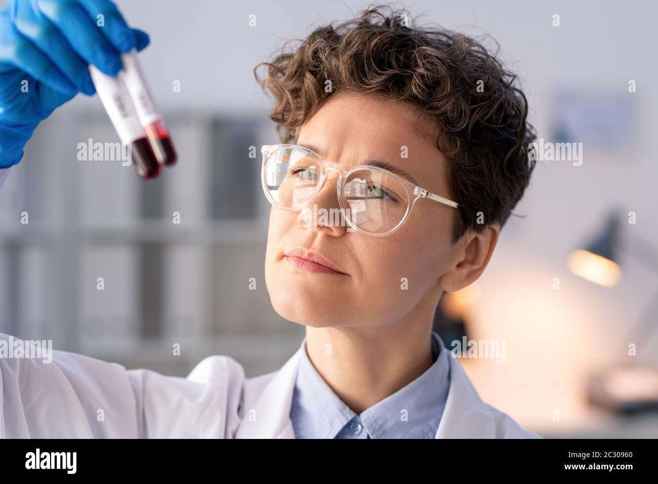 Concentrated laboratory specialist holding lab test of blood samples