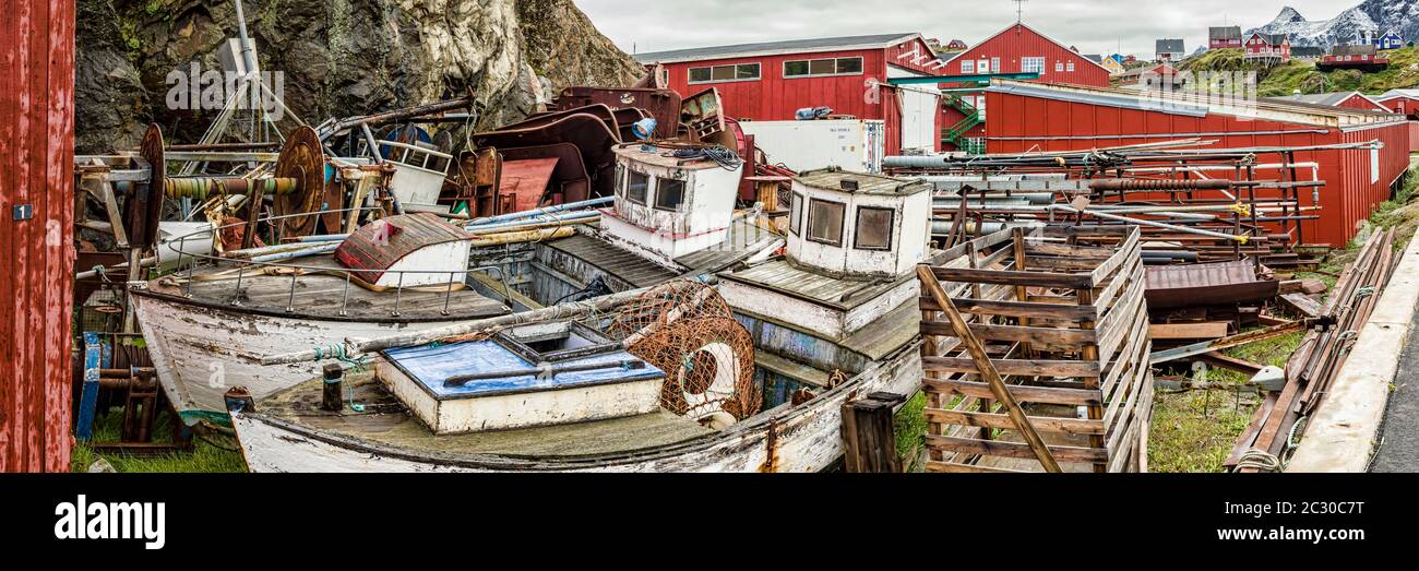 Two old fishing boats and debris lying behind houses in Sisimiut village, Greenland Stock Photo