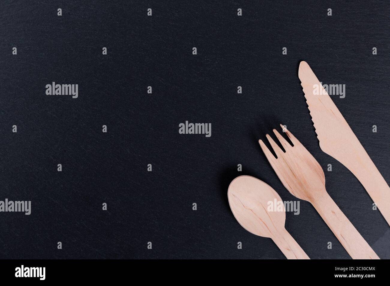 wooden-fork-knife-and-spoon-on-a-black-rock-background-ecology