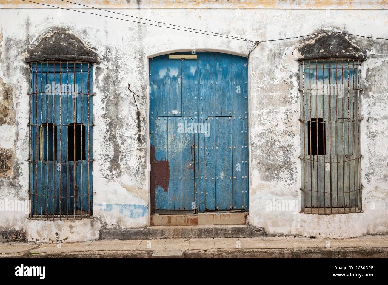 Decayed facade of crumbling plaster and weathered wooden door and windows, Remedios, Cuba Stock Photo
