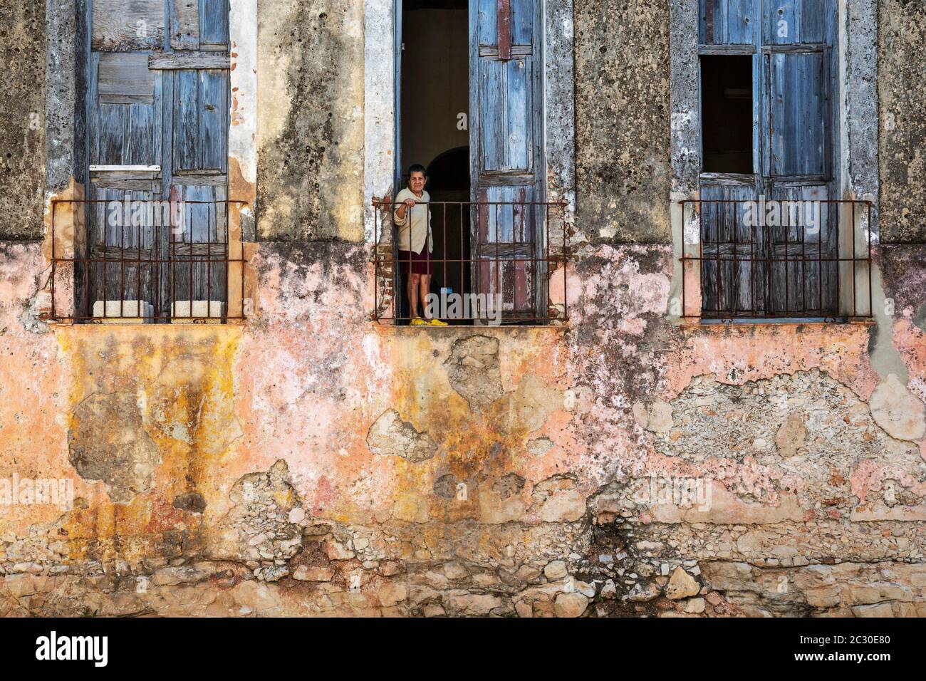 Colours, shapes and textures at the decayed facade of crumbling plaster and weathered wooden doors and windows, Gibara, Cuba Stock Photo
