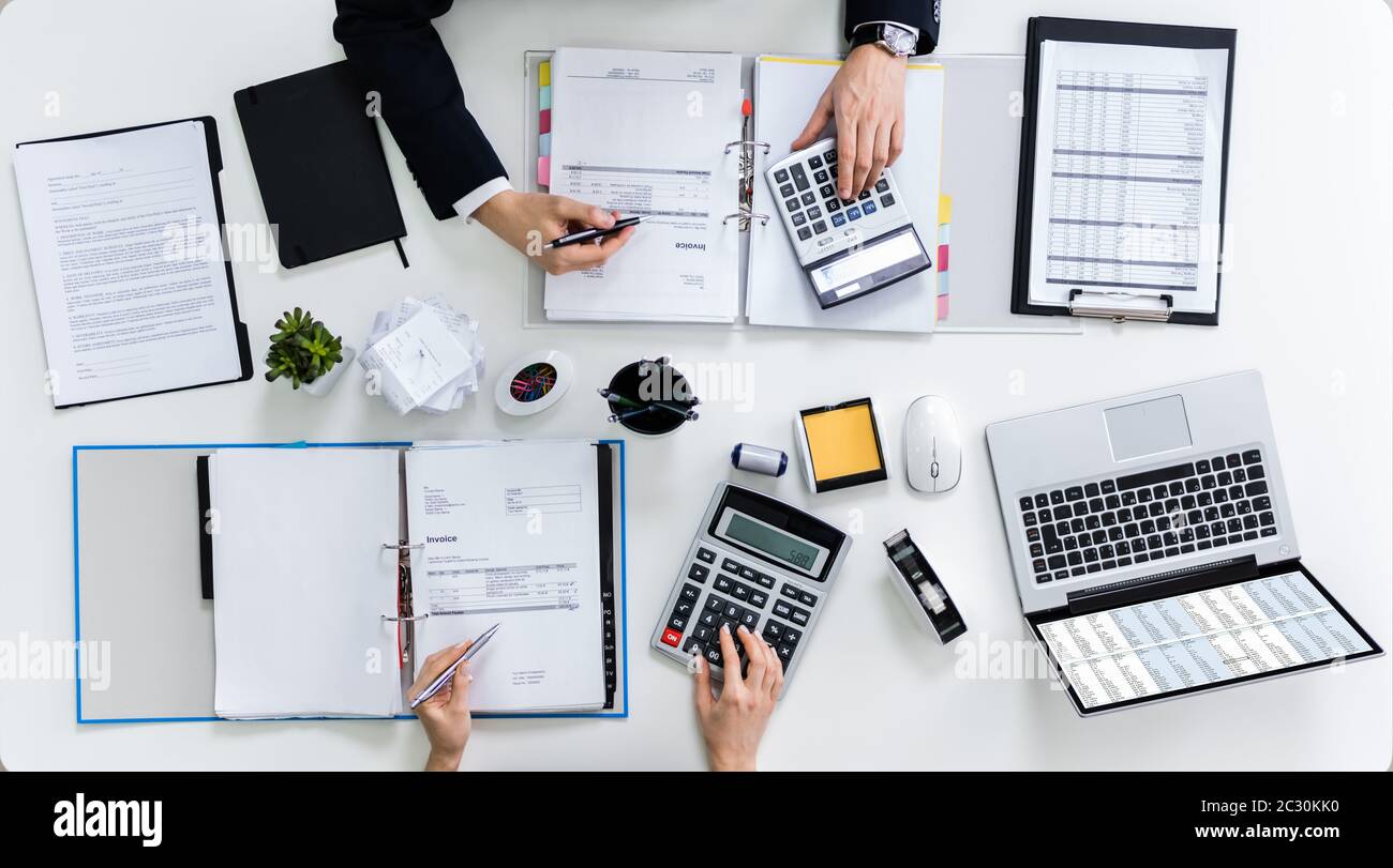High Angle View Of Two Businesspeople Calculating Bills In Office Stock Photo